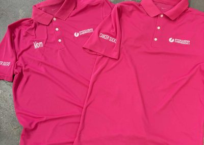 Two pink polo shirts with an embroidered white company logo on the chest for breast cancer awareness by 400 Ink
