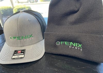 Gray snapback cap and black beanie embroidered with the green Fenix Parts logo by 400 Ink