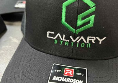 Black Richardson 112 cap embroidered with a green and white Calvary Station logo by 400 Ink