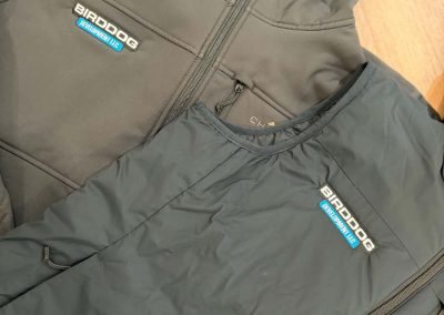 Gray softshell jackets with a small blue and white embroidered chest logo by 400 Ink