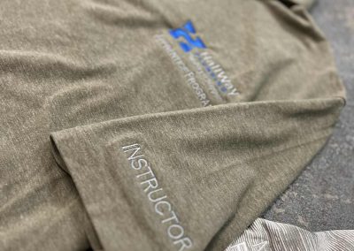 Gray polo with a blue embroidered chest logo and Instructor embroidered on the sleeve by 400 Ink