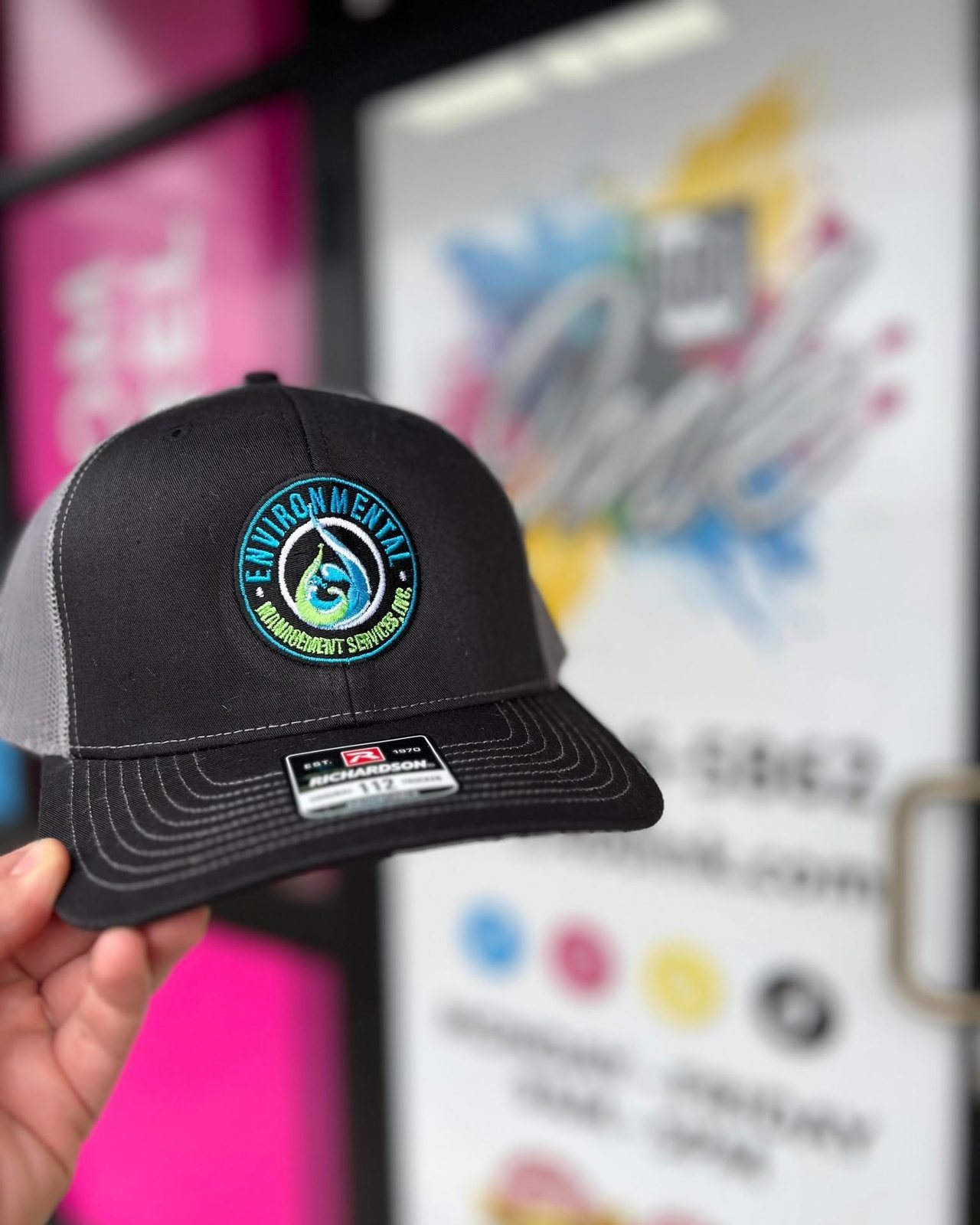 Black trucker hat with an embroidered logo patch by 400 Ink in Dawsonville GA